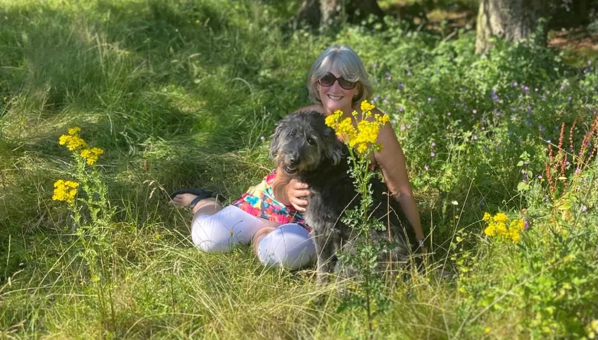 A white woman sits with her 10 year-old working-type labradoodle